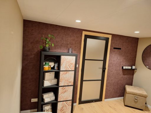 Kamer met een paarse muur, een kast, een deur en een plant op een plank.